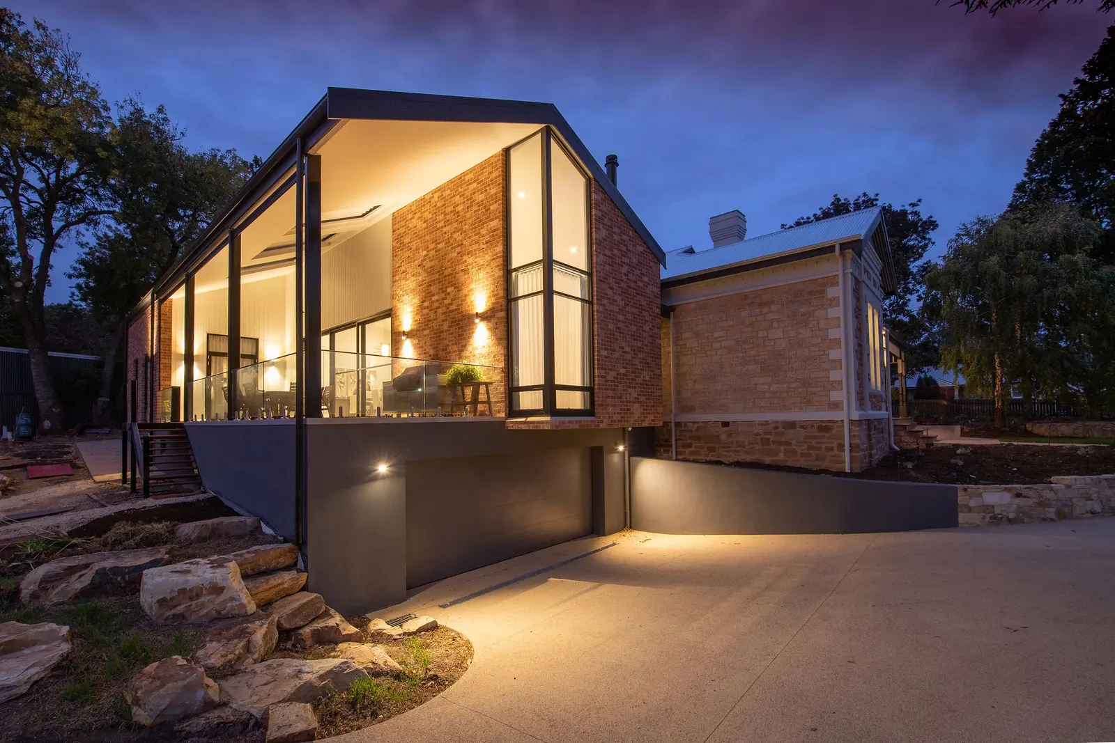 Contemporary brick home with warm architectural lighting at dusk